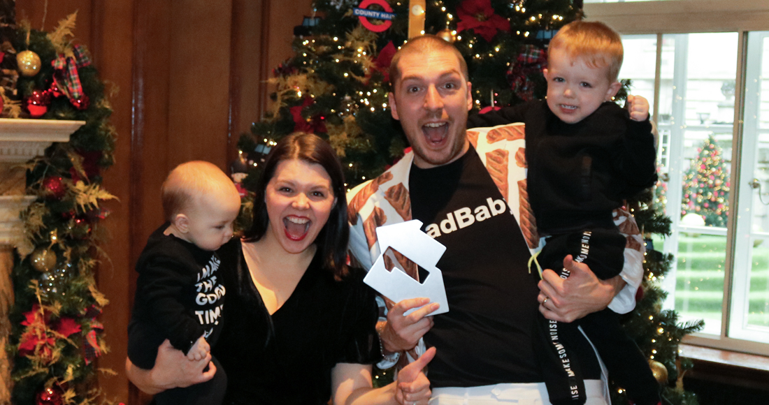 LadBaby and family celebrating with an Official Charts number-one award by a Christmas tree.