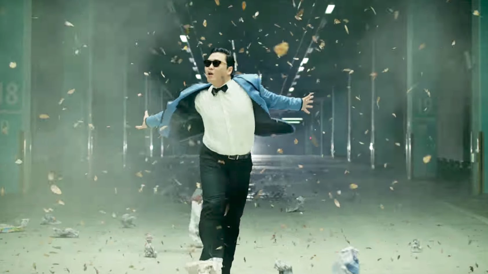 Psy performing the Gangnam Style dance in a debris-filled corridor from the music video.