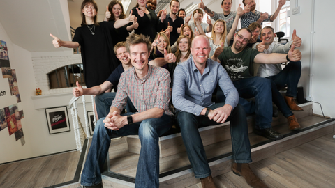 The Distinction team posing on a staircase and giving thumbs-up, with two men seated at the front.