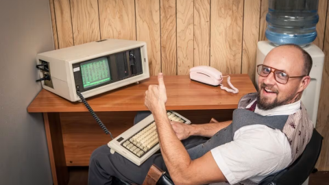 A man on an old computer giving a thumbs up.