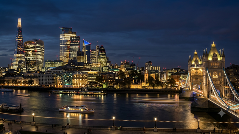The London skyline at night across the Thames, with the lit-up City, the Shard and Tower Bridge.