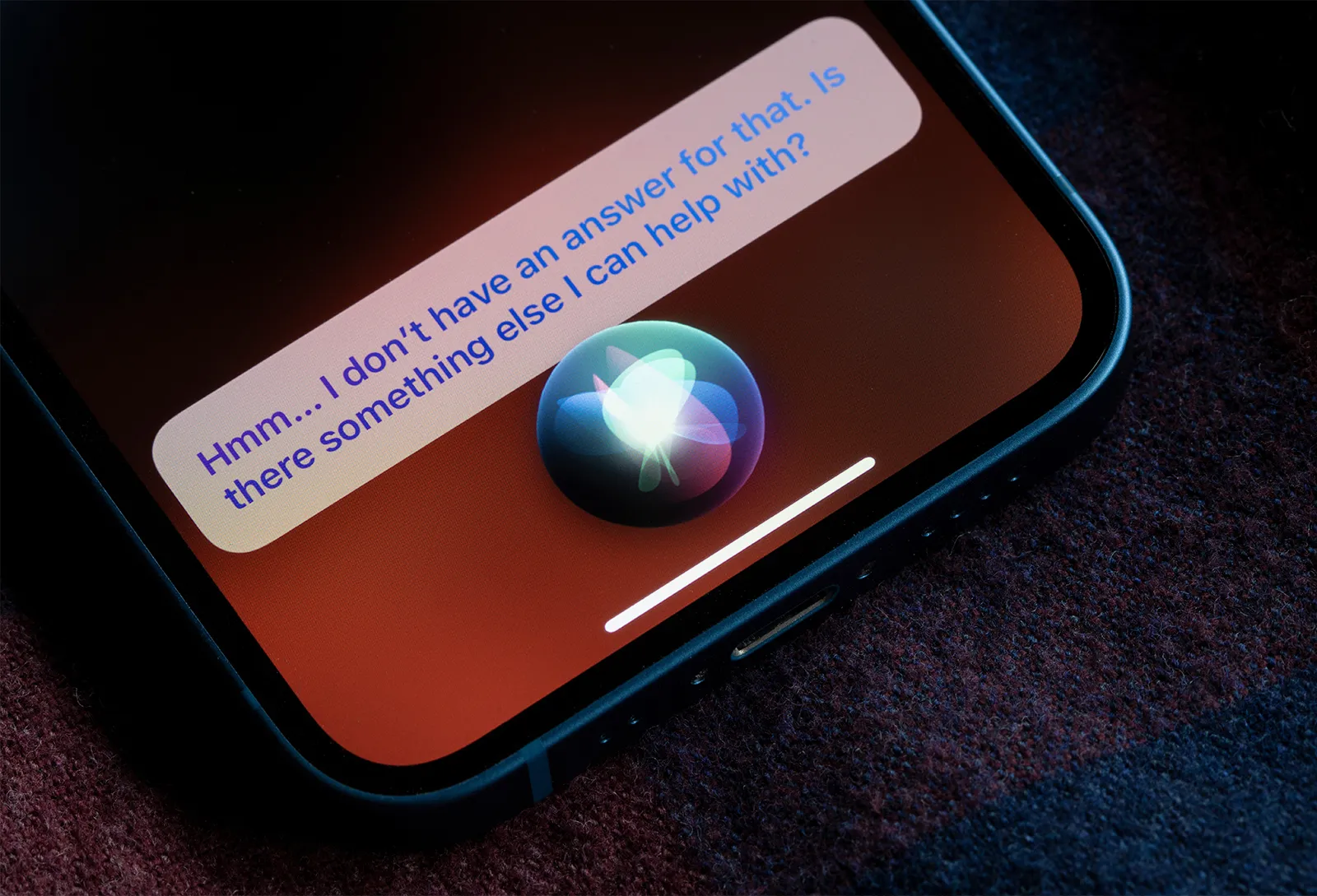 A smartphone showing Siri’s glowing orb and the reply “Hmm… I don’t have an answer for that”.