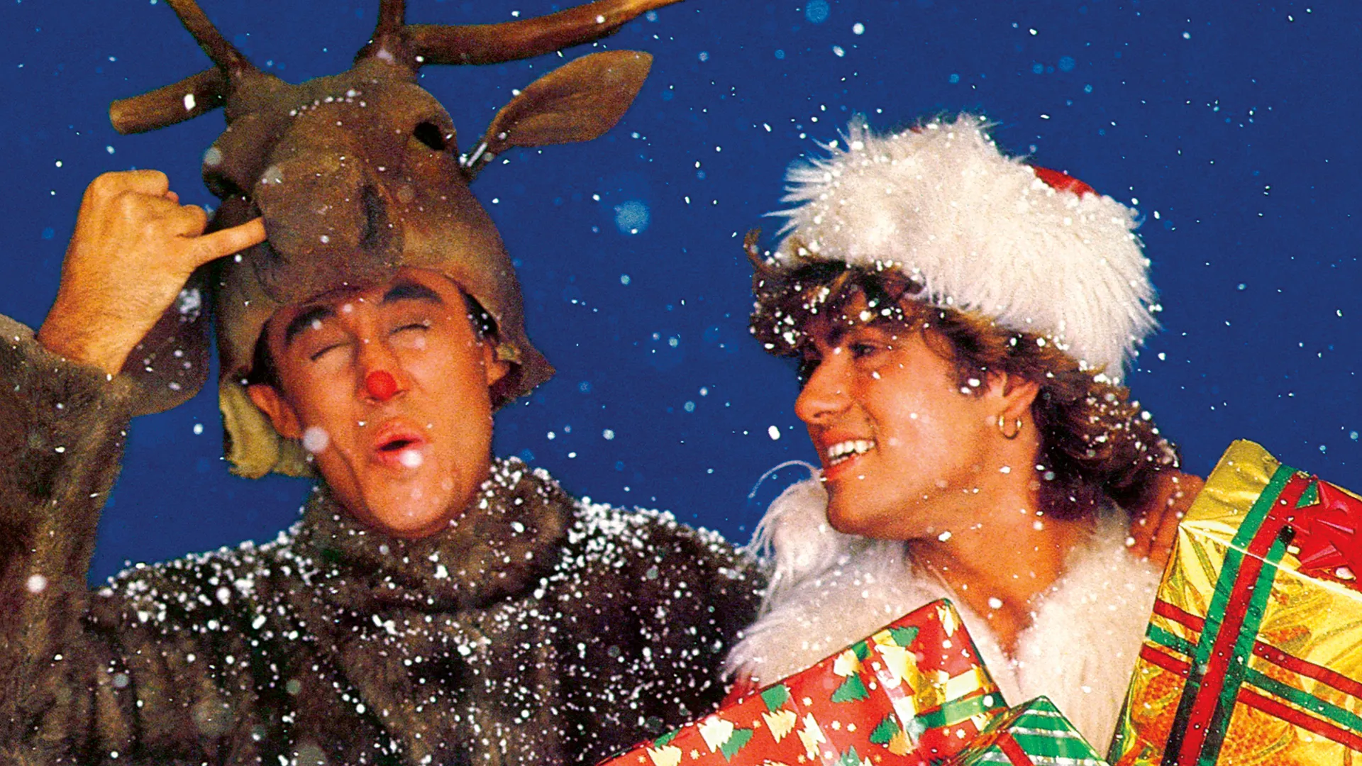 George Michael and Andrew Ridgeley of Wham! in the snowy Last Christmas video, one wearing reindeer antlers.